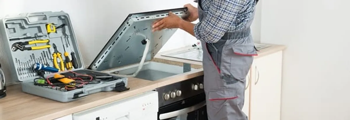 Cooktop repair technician lifting a built-in stovetop for service in Boca Raton, FL