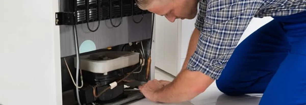 Refrigerator repair technician servicing the compressor and condenser area in Boca Raton, FL